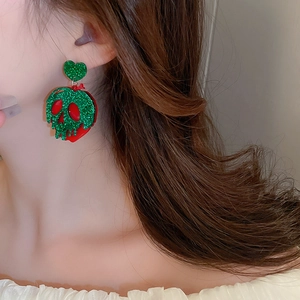 Close-up of Halloween heart skull apple earrings with green glitter and red finish
