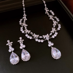 Détail de parure collier et boucles d'oreilles argentées avec cristaux sur fond noir