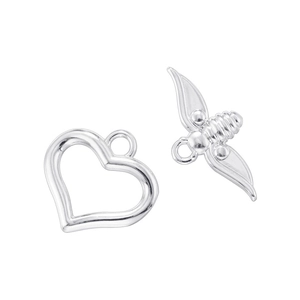 Macro shot of silver heart pendant and detailed bee charm with polished metal finish