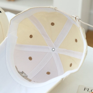 Detail of beige baseball cap interior showing white reinforcement tape and metal buckle