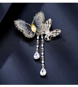 Gros plan d'une broche papillon en zircon avec chaînes à franges sur tissu bleu
