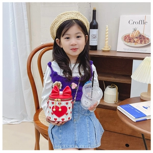 Close-up of children red heart crossbody bag with large bow and golden chain strap