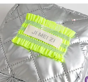 Detail of silver quilted makeup bag with diamond stitching and green label detail