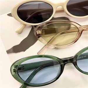 Three pairs of vintage oval sunglasses with colorful frames stacked on a fashion book