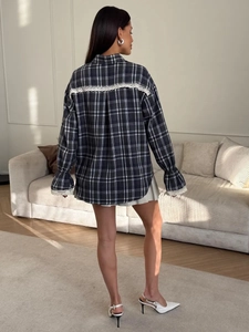 Back view of a black and white plaid shirt featuring delicate lace stitching and flared cuffs