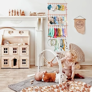 Pink hanging bow organizer with clips and wooden rods for kids room wall storage