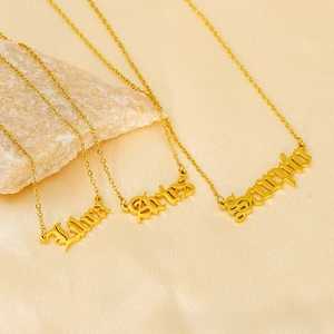 Detailed view of Libra, Aries, and Scorpio nameplate pendants on 18K gold-plated chains