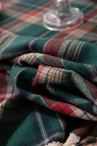Close-up of red and green festive plaid tablecloth fabric texture with soft tassels