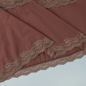 Detailed close-up of mocha brown fabric with delicate floral lace trim on a summer skirt