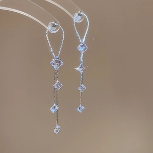 Détail macro de boucles d'oreilles à pompon argenté avec zircone cubique sur support