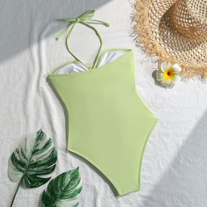 Flat lay of light green halter monokini with tropical decor and summer vacation vibes