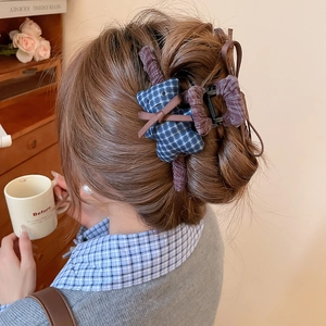 Detail of blue plaid bear hair claw clip worn on hair with purple fabric accents