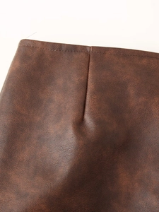 Gros plan des coutures et détails de taille d'une veste en similicuir marron texturé