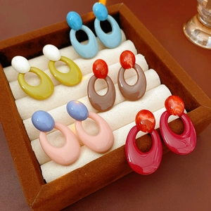 Detail view of oval resin earrings in blue, yellow, and red on a jewelry tray