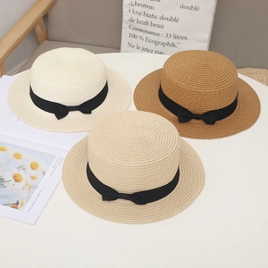 Detailed view of woven straw sun hats in beige and khaki with black ribbon bows
