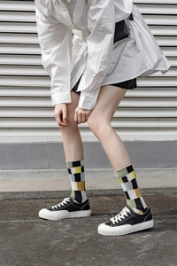 Outdoor shot of stylish crew socks with black, white, yellow, and green plaid pattern