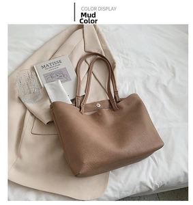 Close-up of litchi grain texture and magnetic buckle closure on a mud color tote bag