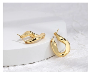 Macro shot of minimalist gold geometric egg-shaped earrings with a polished metallic finish