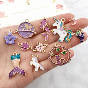Assorted purple enamel charms in hand including cat, mermaid and unicorn DIY jewelry pendants