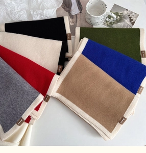 Detail of color-blocked knitted scarves with leather labels and soft cashmere-like texture