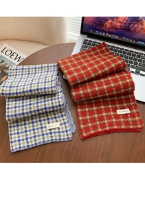 Detail showing folded plaid knit scarves with trendy white labels on a wooden table