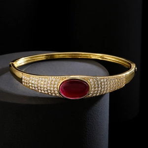 Luxurious gold-plated cuff bracelet featuring a red oval gemstone and pavé zircon accents