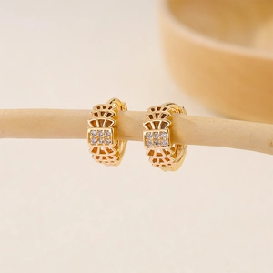 Detail of gold-plated huggie earrings with hollow geometric patterns and square zircon inlay