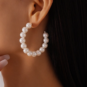 Close-up of elegant large white pearl hoop earring worn by a model in soft lighting