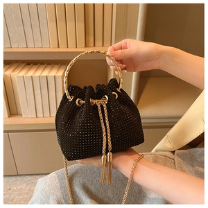 Detail of black rhinestone bucket bag featuring gold ring handle and tassel drawstring