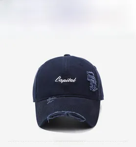 Detailed view of distressed dark blue baseball cap with white Capital embroidery