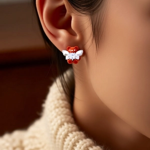 Close-up of red flocked bear stud earring with white wings and inlaid zircon on model