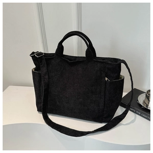 Detailed view of black corduroy tote bag featuring dual handles and adjustable shoulder strap