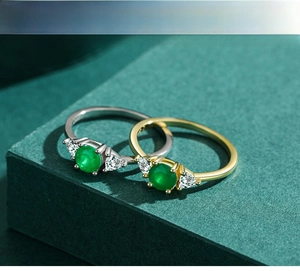 Close-up of gold and silver rings featuring round green emerald-style stones