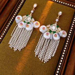 Detail of vintage fan-shaped earrings with pearls and tassels on a green velvet base
