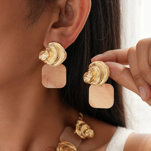 Detail shot of vintage resin square pendant earrings with irregular gold texture on model
