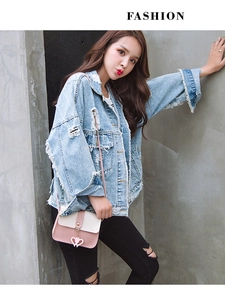 Outdoor street style shot of a light blue distressed denim jacket with fringe tassels