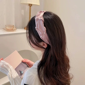 Dettaglio del cerchietto in seta rosa con piccole perle bianche e nodo elegante