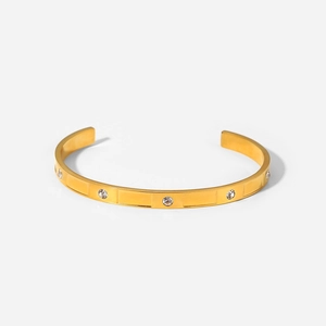 Dettaglio di un bracciale dorato con scanalature rettangolari e zirconi bianchi incastonati