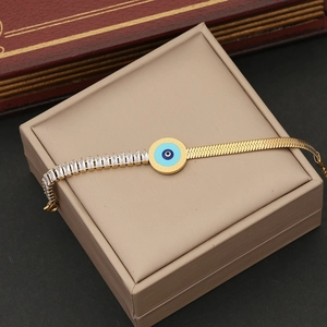 Macro shot of gold-plated evil eye bracelet with blue enamel and zircon on a gift box