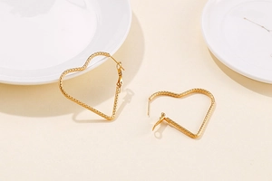 Détail de boucles d'oreilles cœur dorées avec finition métallique texturée et poli brillant
