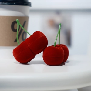 Detalle de joyeros de terciopelo con forma de cereza roja y tallos verdes, abiertos y cerrados