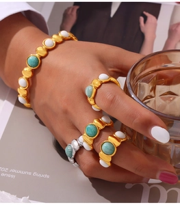 Detail of bohemian gold and silver rings set with turquoise and white stones on hand