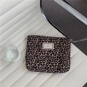 Detail of leopard print canvas makeup bag with Pleasant Time logo on a white seat