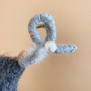 Detail einer flauschigen grauen Haarklammer mit einer zentralen weißen Perle
