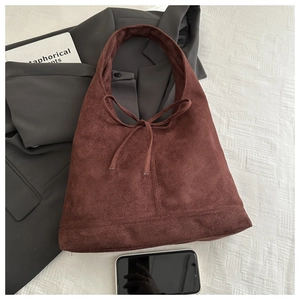 Detail of dark brown matte suede tote bag with ribbon bow and smartphone for scale