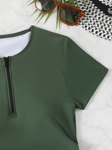 Detail of dark green short sleeve swimsuit top with zipper on white marble with hat