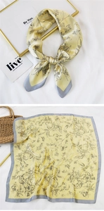 Detail of elegant satin square scarf featuring black botanical prints on pale yellow silk