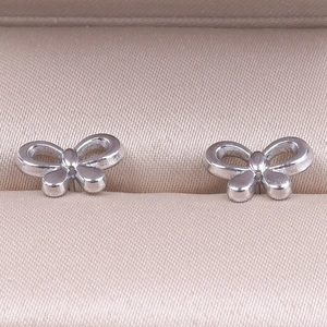 Macro shot of silver bow stud earrings resting in a pink leather jewelry display box