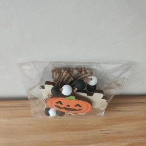 Nahaufnahme von Halloween-Kürbis-Holzscheibe mit schwarz-weißen Perlen und Hanf-Quaste
