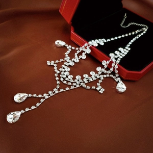 Detailed macro view of silver tassel necklace with zircons resting on a red jewelry gift box